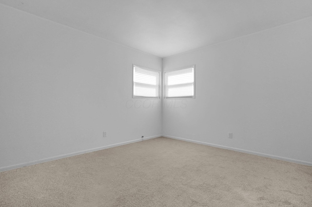 unfurnished room with light colored carpet and baseboards