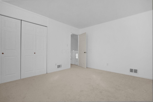unfurnished bedroom featuring carpet floors, a closet, and visible vents