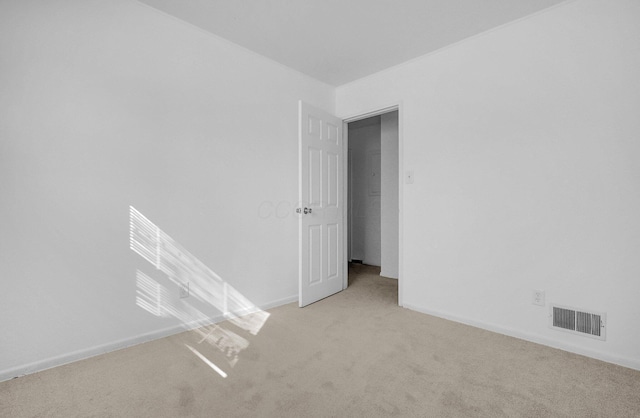 spare room with light colored carpet, visible vents, and baseboards