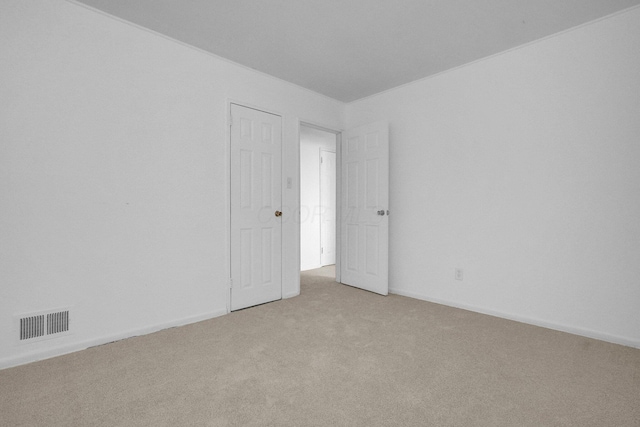 unfurnished room with light colored carpet, visible vents, and baseboards