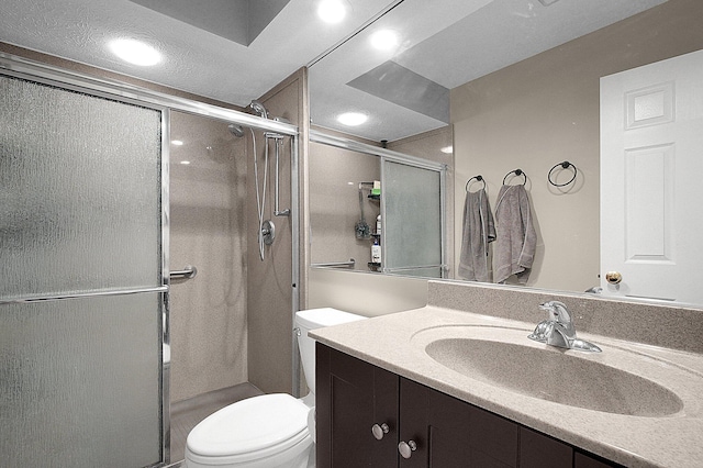 bathroom with a shower stall, toilet, and vanity