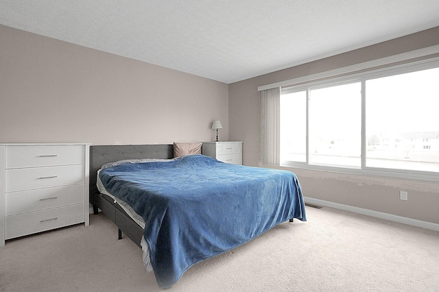 bedroom featuring visible vents, light colored carpet, a textured ceiling, and baseboards