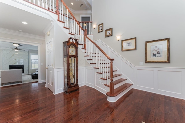 stairway with crown molding, a decorative wall, and wood finished floors