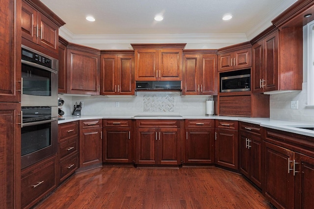 kitchen featuring decorative backsplash, appliances with stainless steel finishes, dark wood-type flooring, ventilation hood, and light countertops