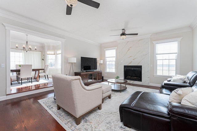 living room featuring a high end fireplace, a healthy amount of sunlight, crown molding, and wood finished floors