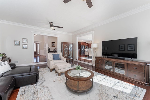 living room with crown molding, ceiling fan, and wood finished floors