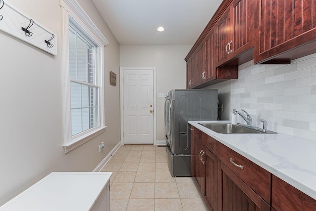 clothes washing area featuring cabinet space, plenty of natural light, light tile patterned floors, and a sink