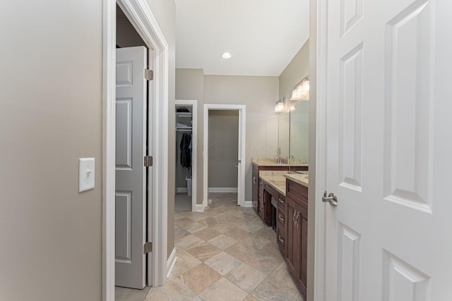 bathroom featuring a spacious closet, vanity, and baseboards