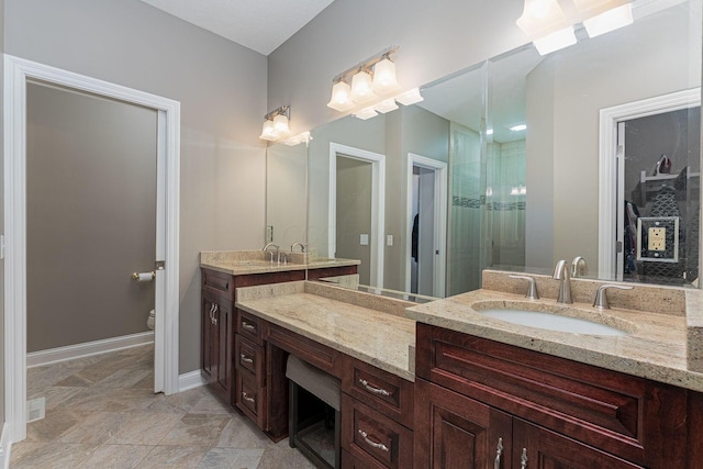 bathroom with a shower, vanity, toilet, and baseboards