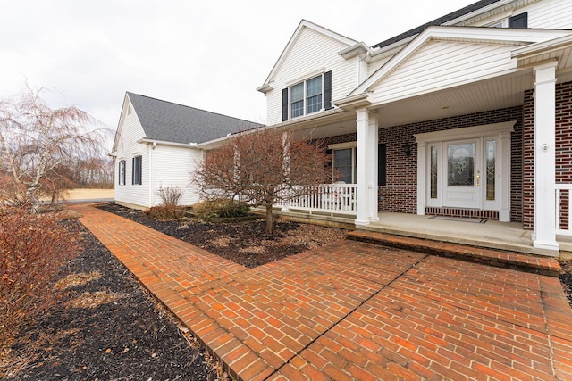 exterior space with a porch and brick siding