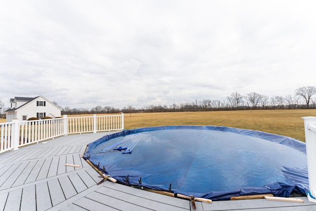 view of swimming pool featuring a covered pool, a lawn, and a wooden deck