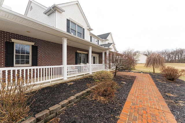 view of side of property with covered porch and brick siding