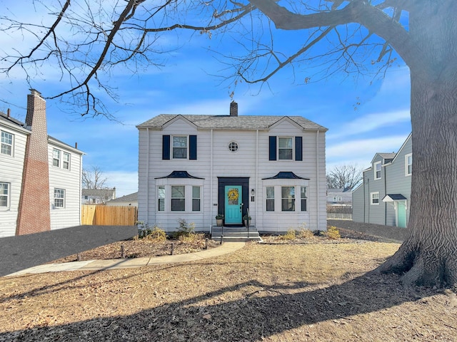 view of front of property with a chimney and fence