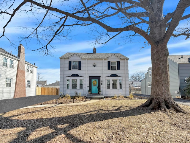 view of front of house with entry steps, fence, and a chimney