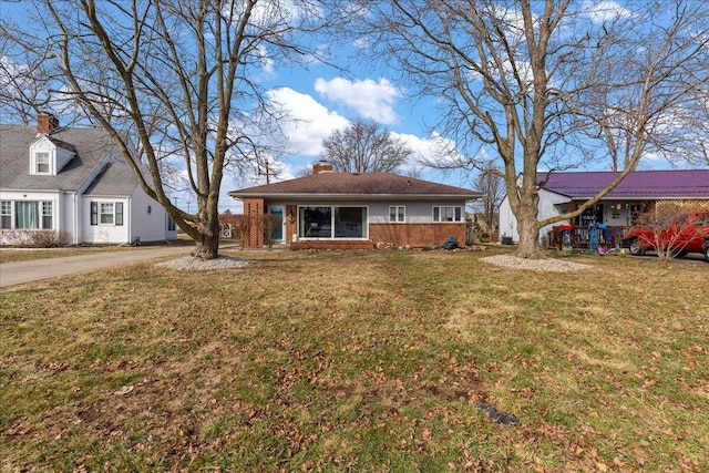 view of front facade featuring brick siding, a chimney, and a front lawn