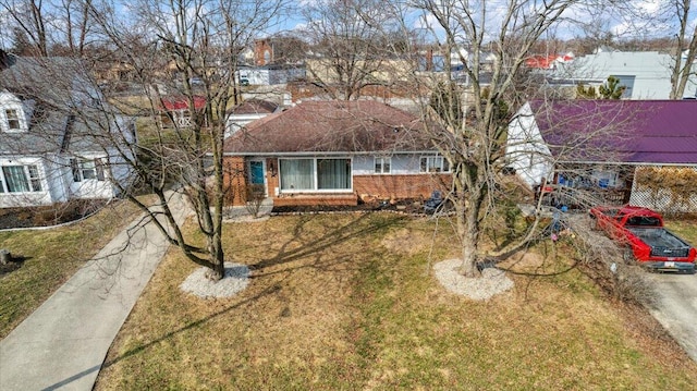 view of front facade featuring a front yard, concrete driveway, and brick siding