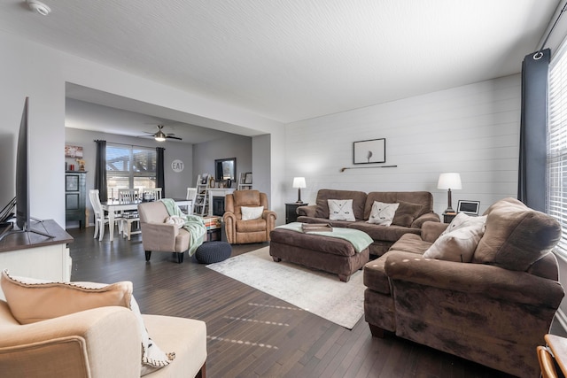 living room with ceiling fan, dark wood-style flooring, and a textured ceiling