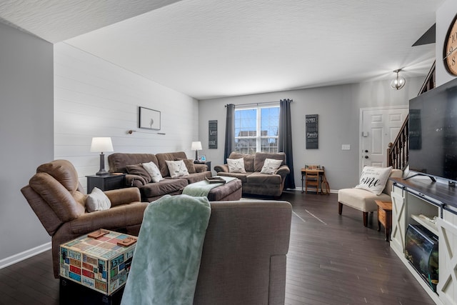 living room with stairs, baseboards, dark wood finished floors, and a textured ceiling