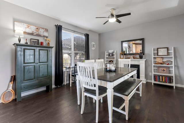 dining room with ceiling fan, wood-type flooring, a fireplace, and baseboards