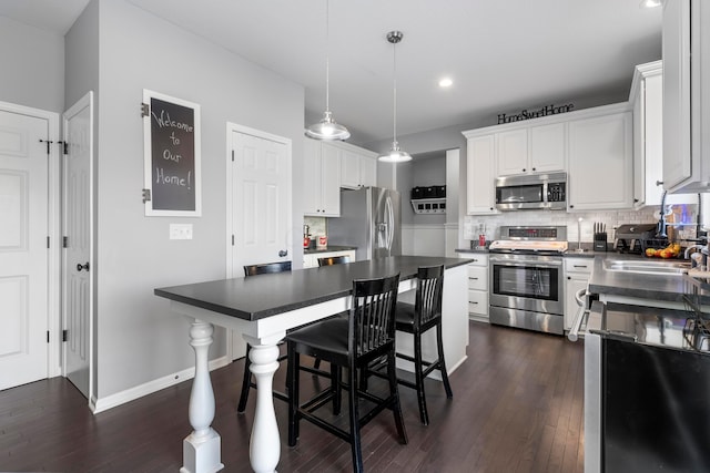 kitchen featuring dark countertops, tasteful backsplash, appliances with stainless steel finishes, and dark wood finished floors