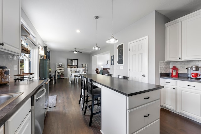 kitchen with dark countertops, tasteful backsplash, dark wood-type flooring, and dishwasher