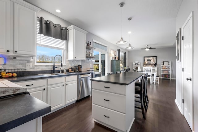 kitchen featuring a sink, white cabinets, stainless steel dishwasher, decorative backsplash, and dark countertops