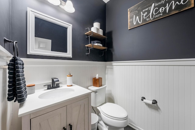 bathroom with toilet, vanity, and wainscoting