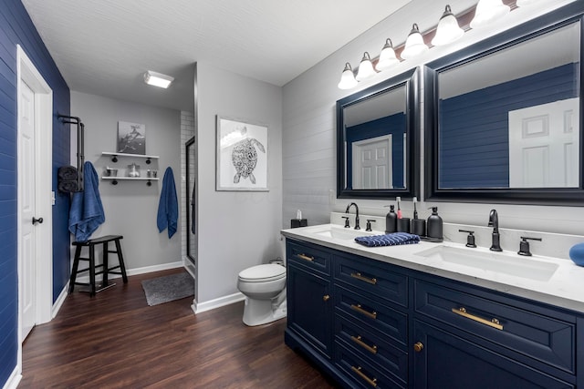 bathroom with toilet, double vanity, a sink, and wood finished floors