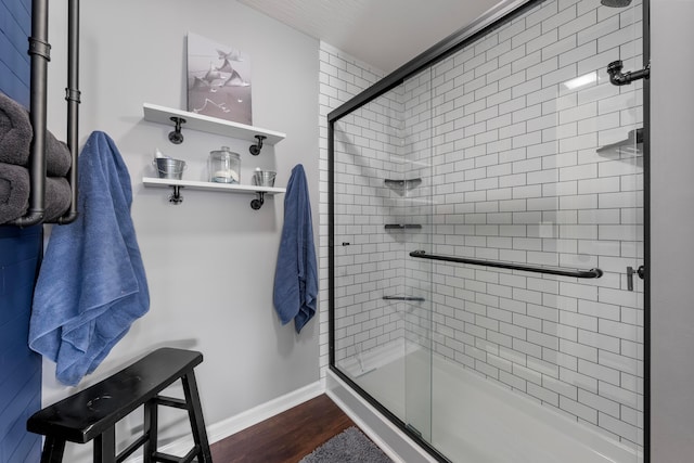 bathroom with a shower stall, baseboards, and wood finished floors