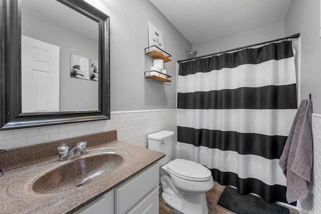 full bath with tile walls, curtained shower, toilet, wainscoting, and vanity