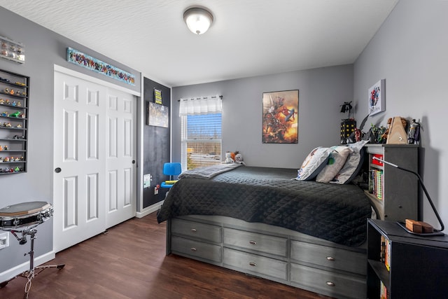 bedroom with dark wood-style floors, a closet, and baseboards