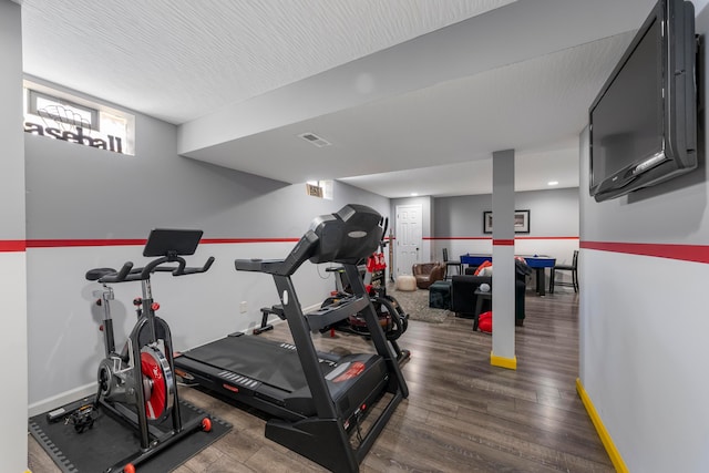 exercise area with visible vents, baseboards, and wood finished floors