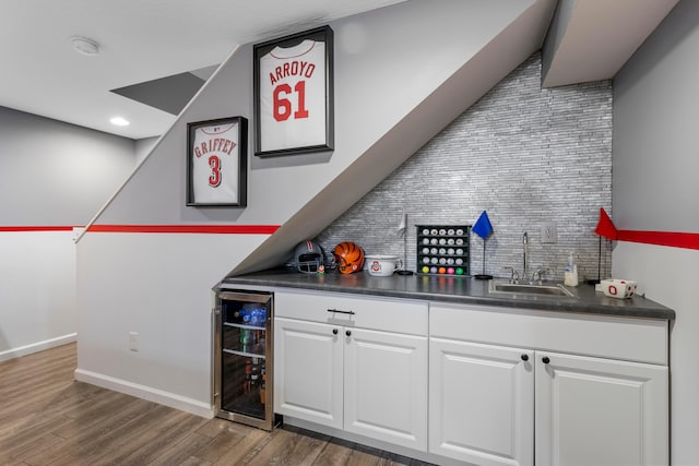 bar featuring wine cooler, wood finished floors, a sink, backsplash, and wet bar