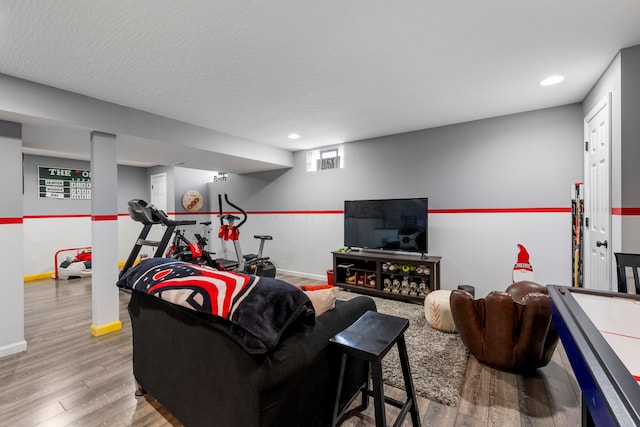 living room featuring a textured ceiling, baseboards, wood finished floors, and recessed lighting