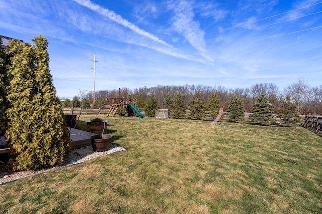 view of yard with a playground, fence, and a wooden deck