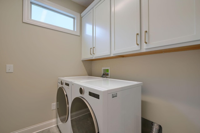 clothes washing area featuring washer and clothes dryer, cabinet space, and baseboards