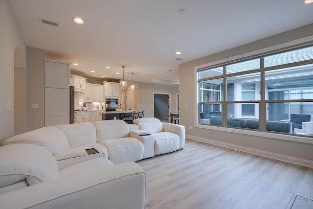 living room with light wood-type flooring, recessed lighting, visible vents, and baseboards