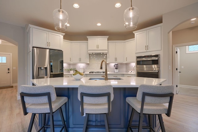 kitchen featuring appliances with stainless steel finishes, arched walkways, a sink, and light countertops