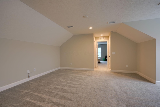 additional living space featuring visible vents, a textured ceiling, and baseboards