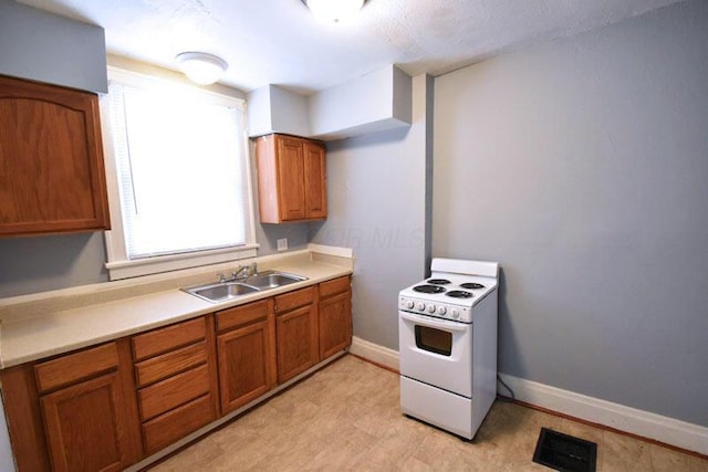 kitchen with brown cabinetry, electric stove, visible vents, and a sink