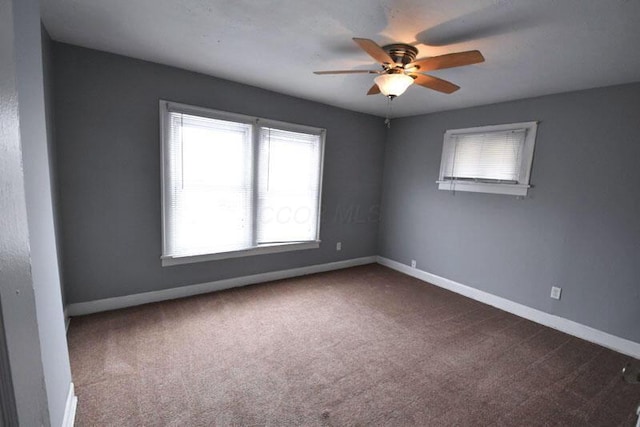 carpeted spare room with ceiling fan and baseboards