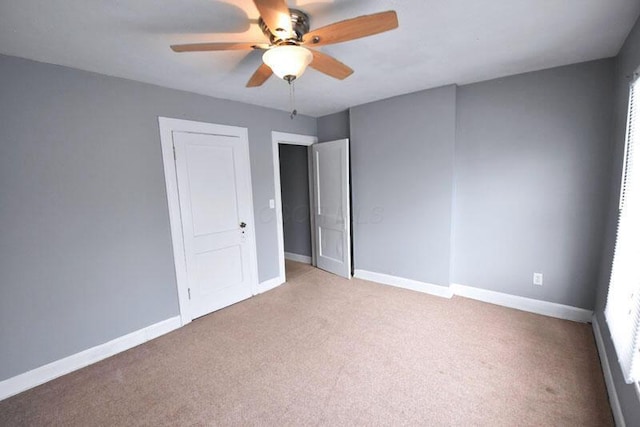 unfurnished room with a ceiling fan, light colored carpet, and baseboards