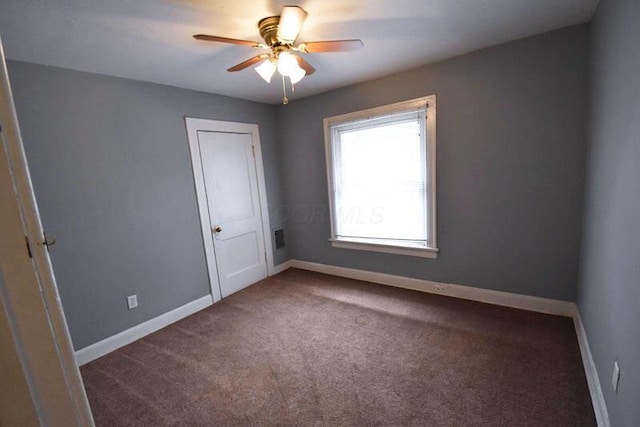 carpeted spare room featuring a ceiling fan, visible vents, and baseboards