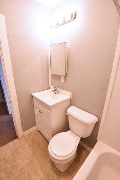 full bathroom with a tub to relax in, toilet, and vanity