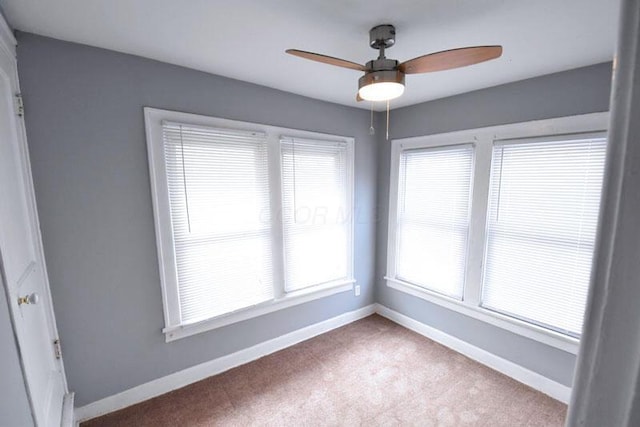 carpeted spare room with a ceiling fan and baseboards