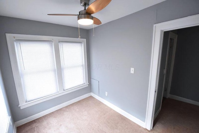 empty room with carpet floors, baseboards, and a ceiling fan