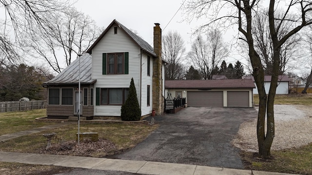 view of front of home with a chimney, a detached garage, and fence