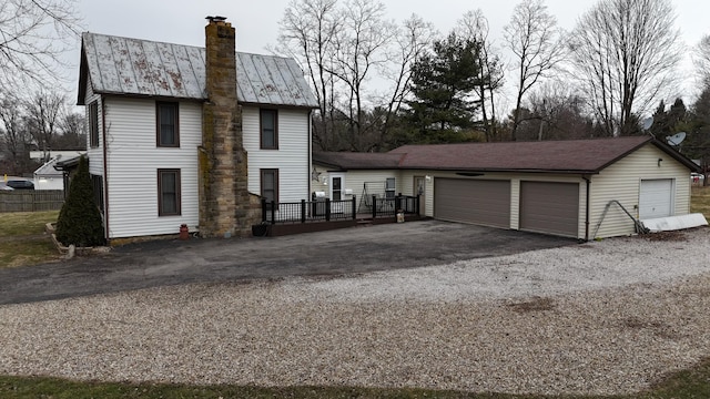 view of side of property featuring a deck, metal roof, a garage, and a chimney