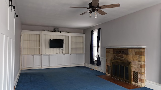 unfurnished living room with a fireplace, baseboards, ceiling fan, and dark colored carpet