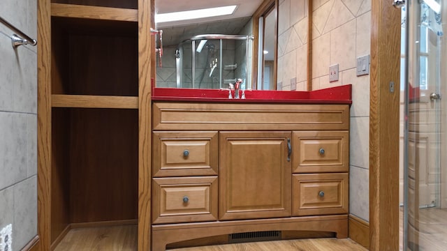 full bath featuring visible vents, a stall shower, wood finished floors, tile walls, and vanity